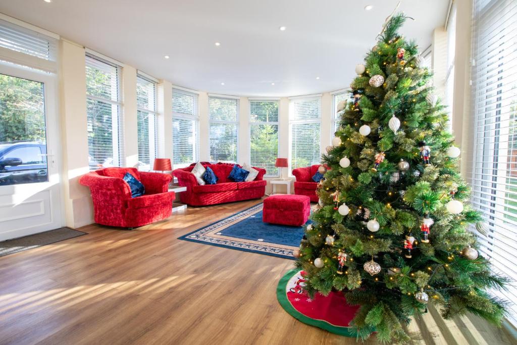 a christmas tree in a living room with red furniture at Stunning Apartment in Victorian Villa with Garden in Torquay