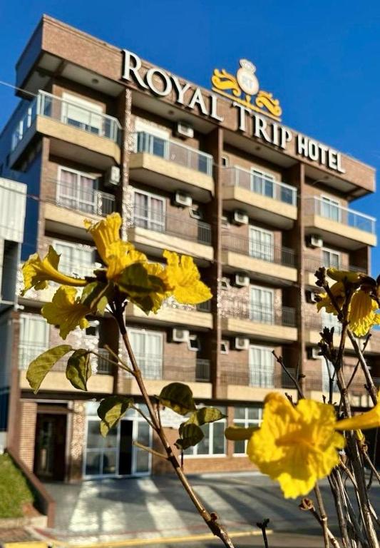 a hotel with yellow flowers in front of it at Royal Trip Hotel in Guarapuava