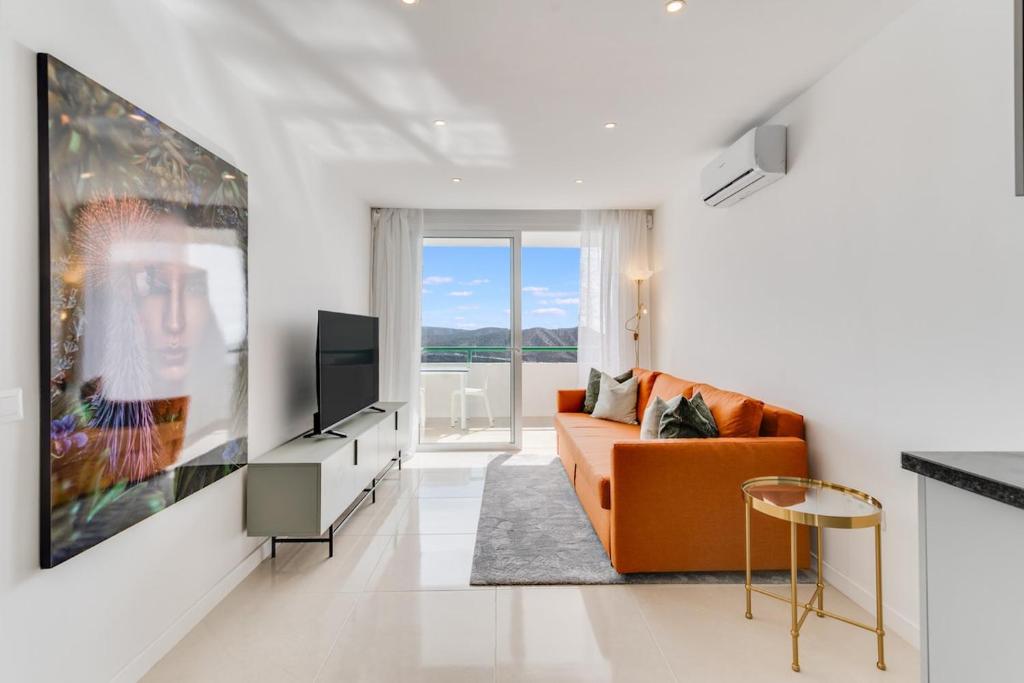 un salon avec un canapé orange et une télévision dans l'établissement Sea View Monteparaiso, à Puerto Rico