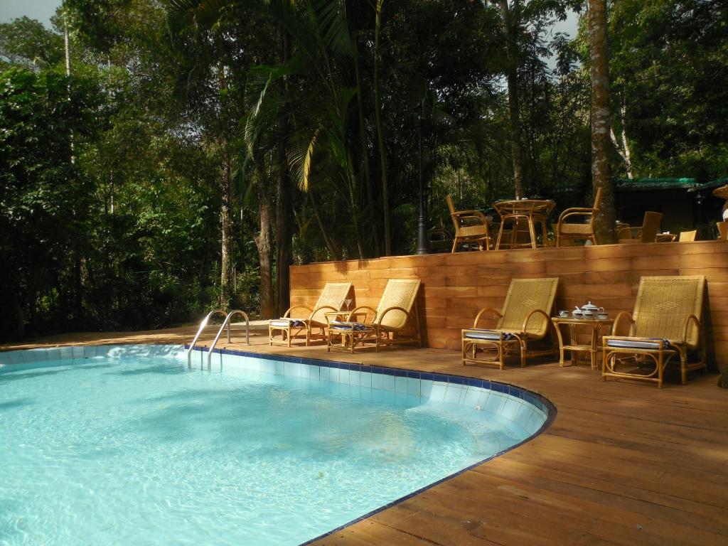 a swimming pool with chairs and a table on a wooden deck at Le leopard d 'argent in Kandy