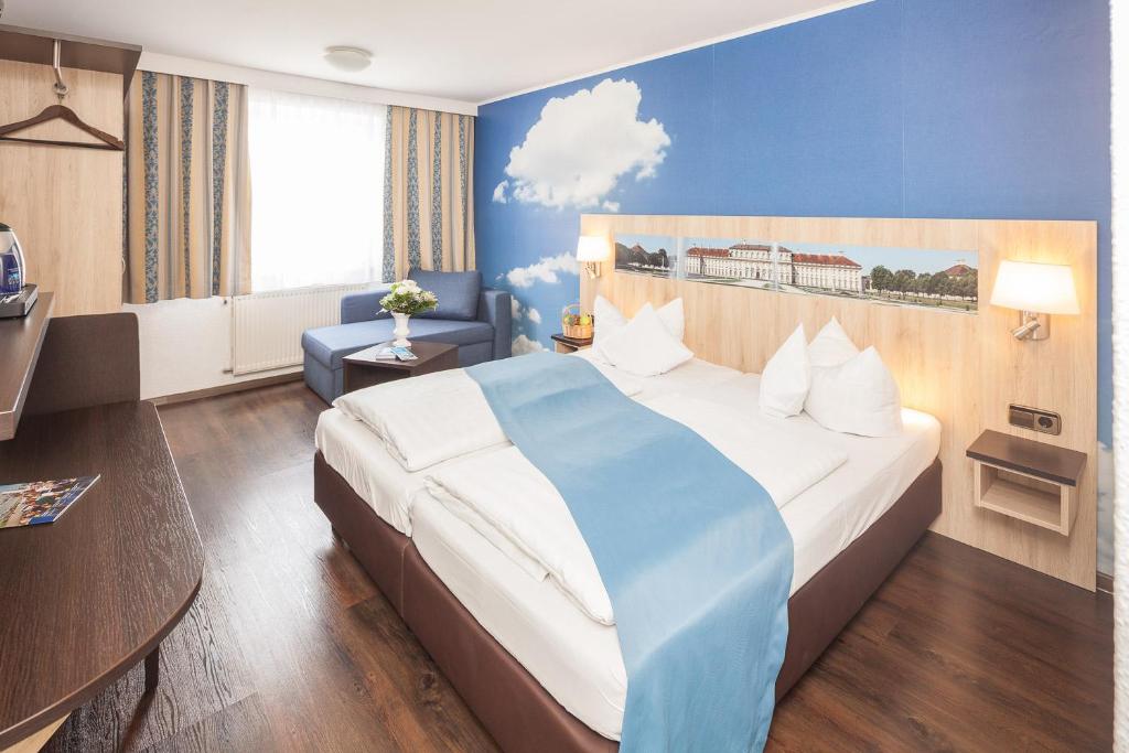Habitación de hotel con cama grande y pared azul en Hotel Blauer Karpfen, en Oberschleissheim