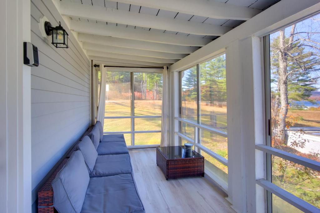a screened in porch with a blue couch and windows at Lake-View Spofford Apartment w/ Shared Dock! in Spofford