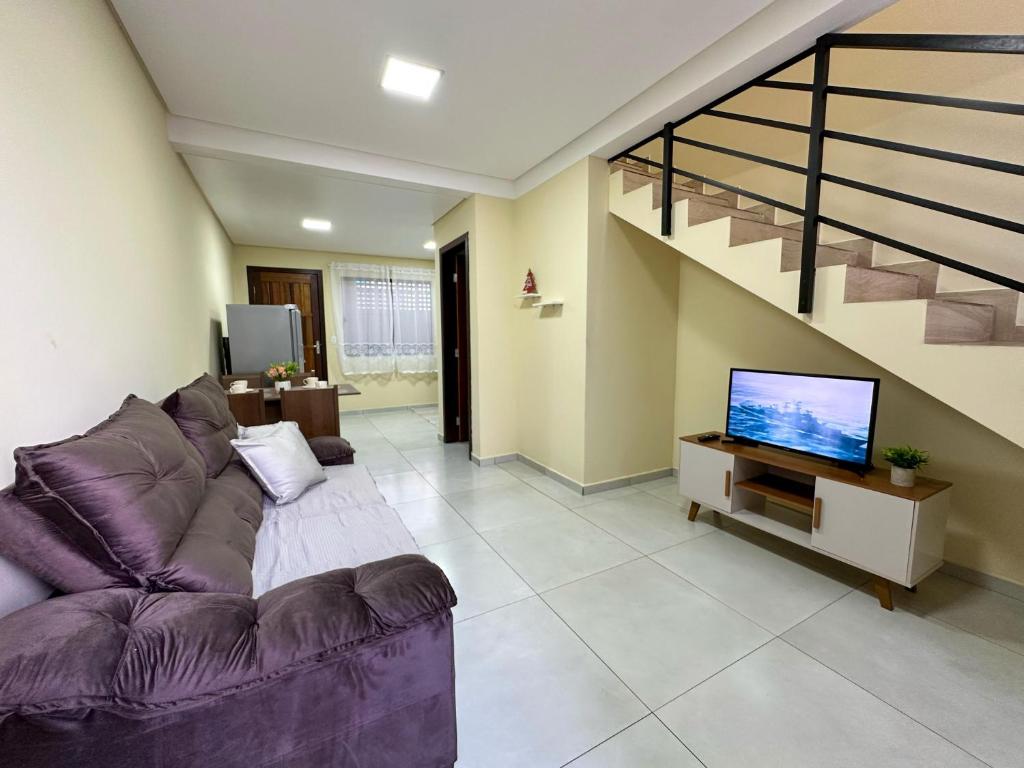 a living room with a purple couch and a tv at Espaçosa casa com WI-FI Perto do Aroporto - Conforto e Praticidade in Joinville