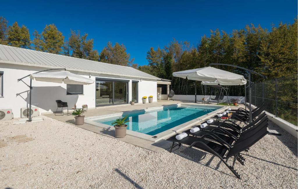 Una piscina con sillas y sombrillas al lado de una casa. en Stunning Home In Zminj, en Jurići