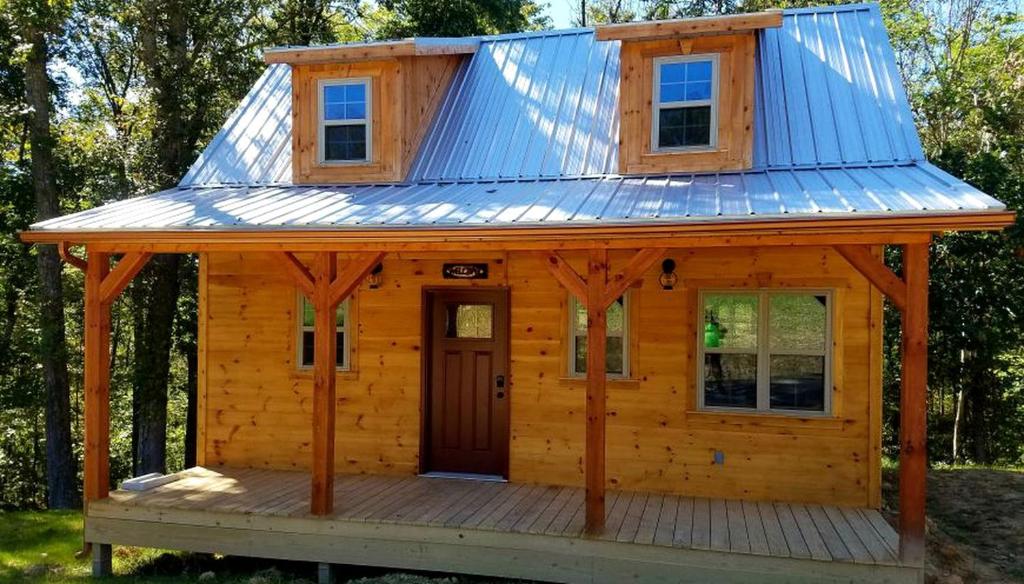 a cabin with a tin roof on a deck at Rustic Family-Friendly Accommodation with Jacuzzi near Huntington, West Virginia in Genoa