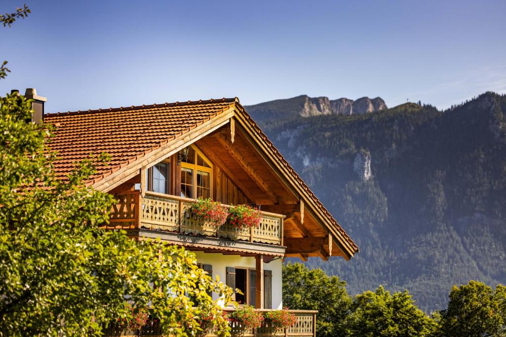 a wooden house with potted plants on a balcony at Ferienwohnung Roislerlehen in Bischofswiesen