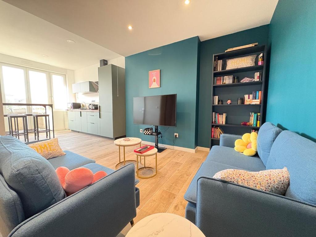 ein Wohnzimmer mit 2 blauen Sofas und einem TV in der Unterkunft Appartement Pop et coloré au coeur de Dunkerque in Dunkerque
