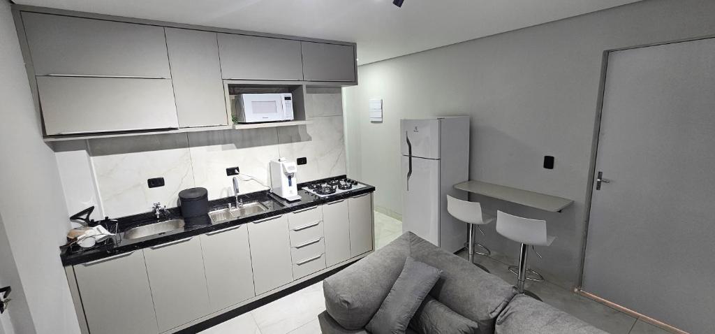 een keuken met witte kasten en een bank in een kamer bij Kitnet Cic in Curitiba