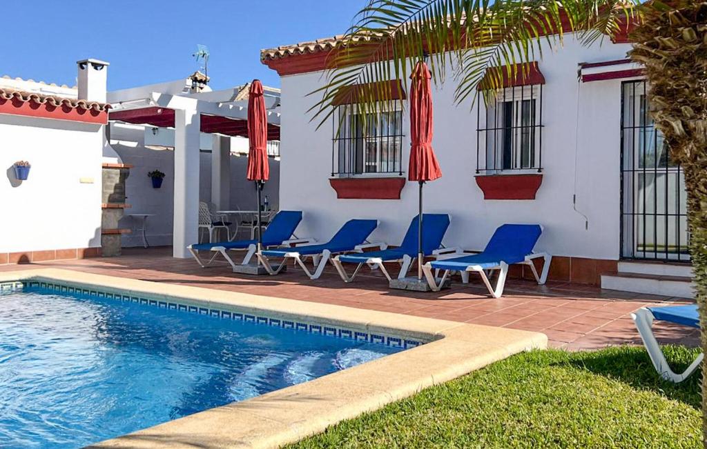 ein Pool mit Stühlen und Sonnenschirmen neben einem Haus in der Unterkunft Gorgeous Home In Chiclana De La Fronter in Chiclana de la Frontera