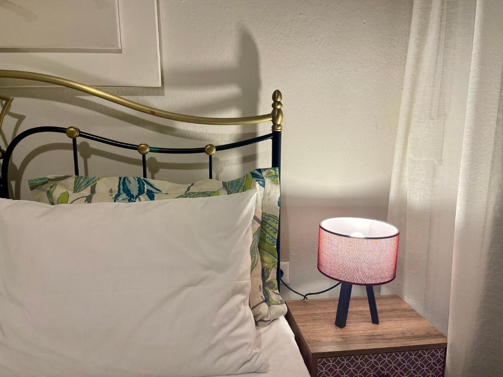a bed with a white pillow and a pink lamp at Chari's Apartment in Tríkala