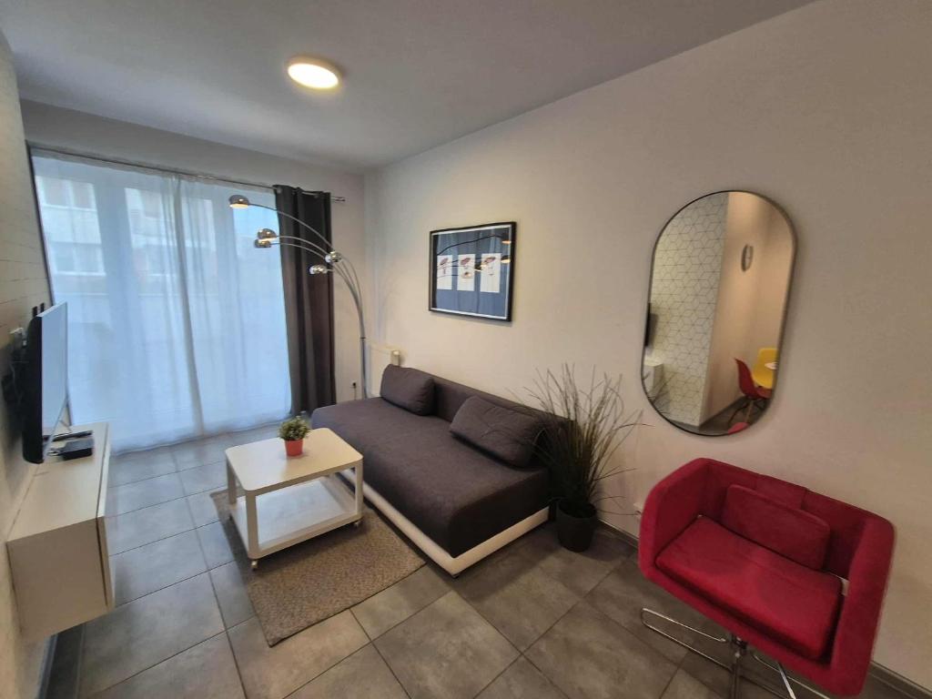 a living room with a couch and a red chair at Mieszkanie z tarasem - Rybacka in Władysławowo