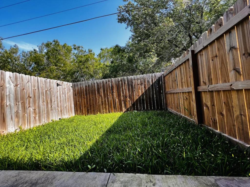 a fence with a yard with green grass next to it at Hummingbird Haven 1 in Pharr