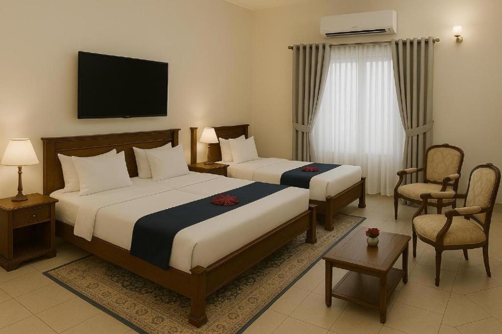 a hotel room with two beds and a tv at The Serenity Inn Family Hotel in Karachi