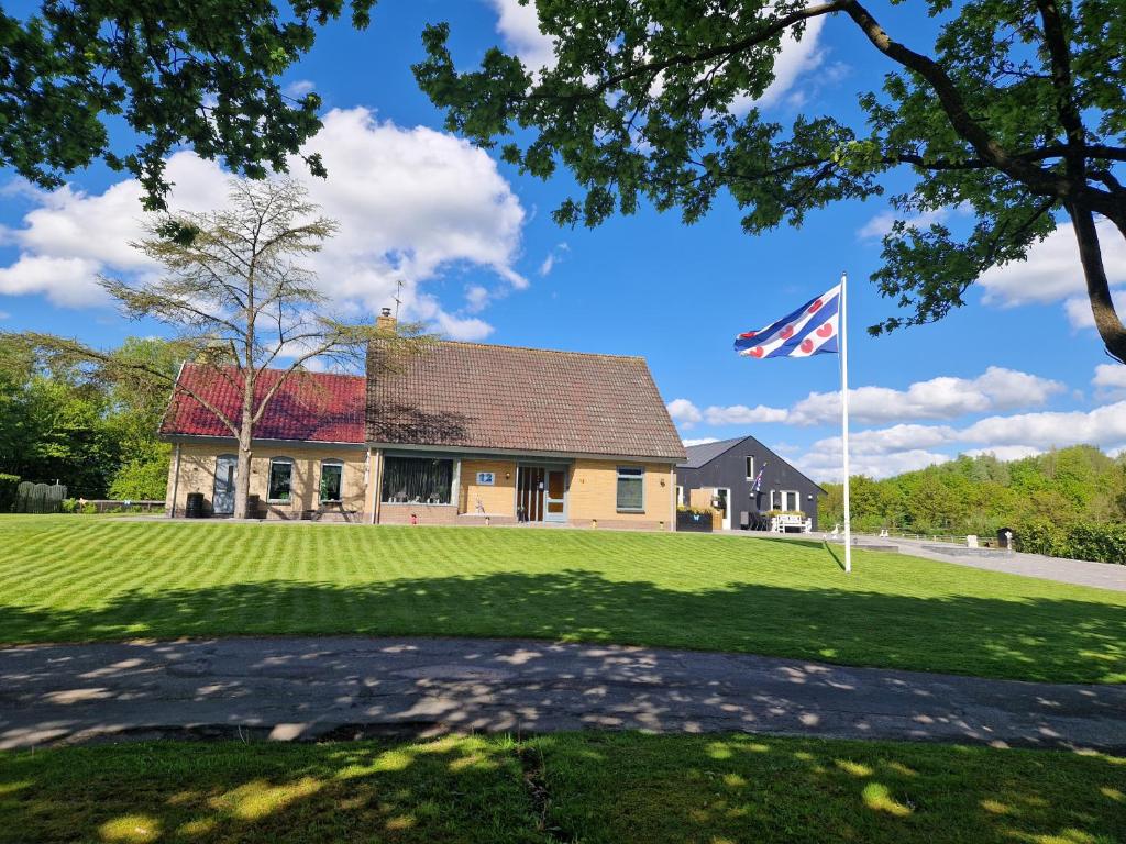 una casa con una bandera delante de un patio en Grutsk op 12, en Drachten