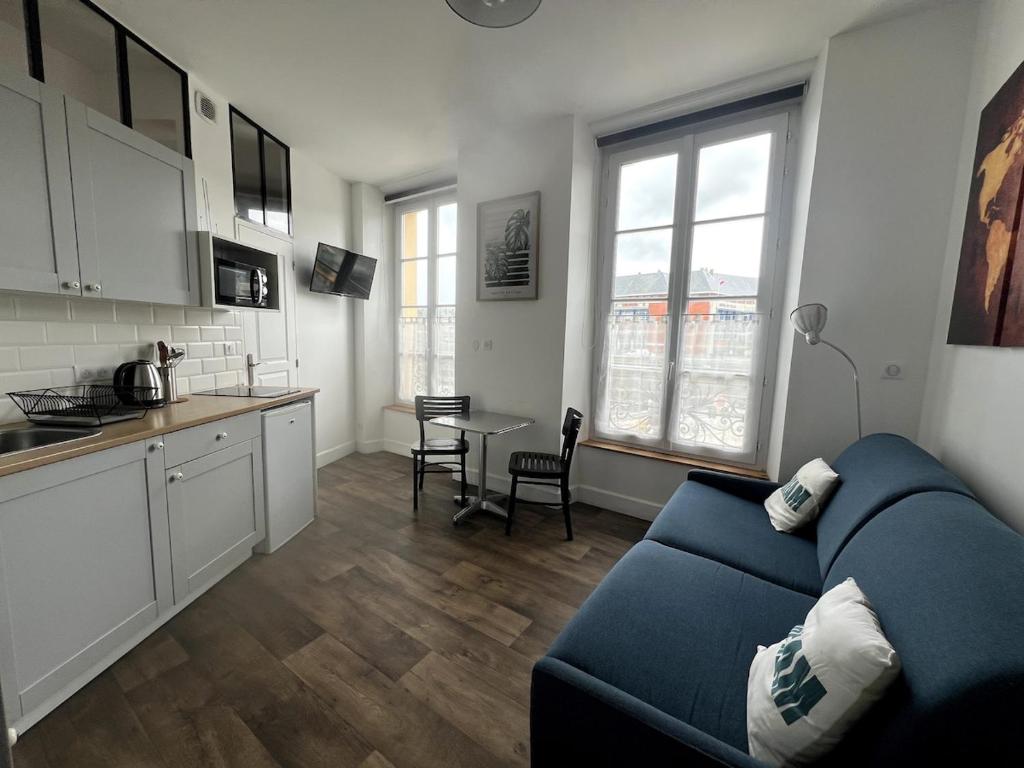 een woonkamer met een blauwe bank en een keuken bij Marc 3 in Saint-Valéry-en-Caux