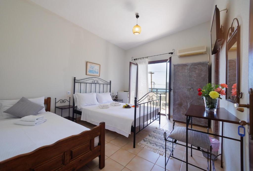 1 dormitorio con 2 camas, mesa y balcón en LITHOS by the sea, en Neon Oitilon