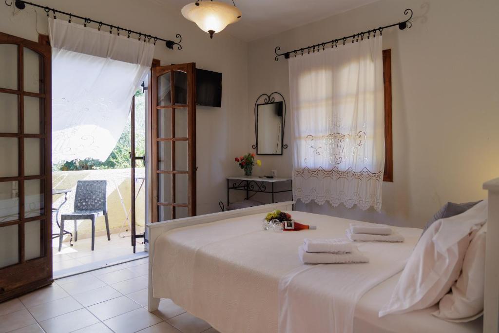 a bedroom with a large white bed and a balcony at LITHOS by the sea in Neon Oitilon