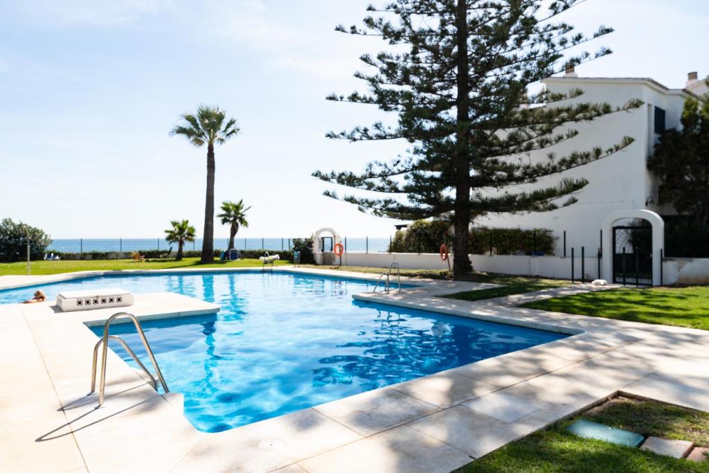 a swimming pool with a table and a tree at Newly Renovated 2 Bedroom Beachfront House in Sitio de Calahonda