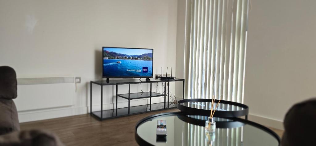 a living room with a tv and a glass table at Cozy Broad Street Apartment Central and Comfortable in Birmingham