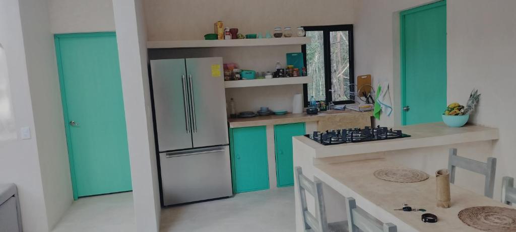 une cuisine avec des armoires vertes et un réfrigérateur dans l'établissement Casabel Tulum jungle experience, à Cobá