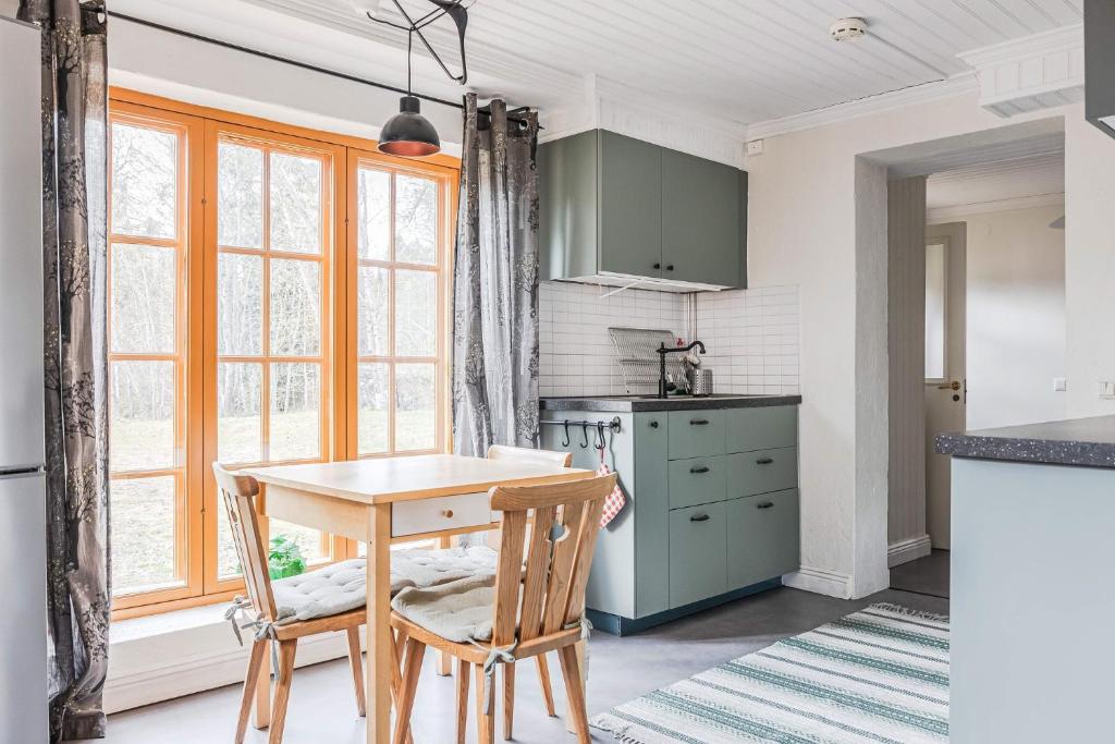 a kitchen with green cabinets and a table and chairs at Franshammars vandrarhem in Hassela