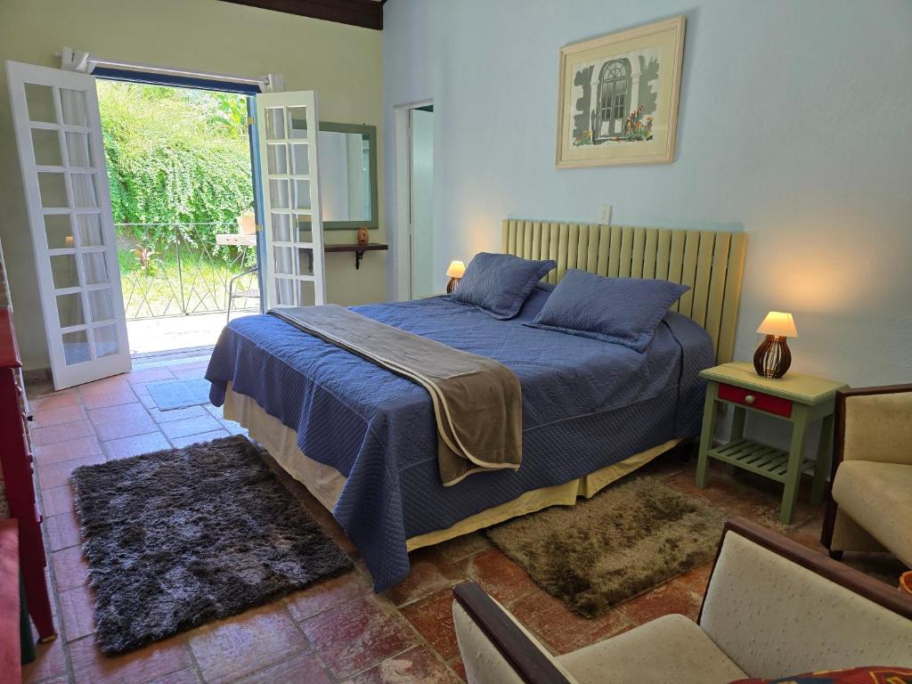 a bedroom with a bed with a blue blanket at Pousada Quintal das Hortênsias in Salesópolis