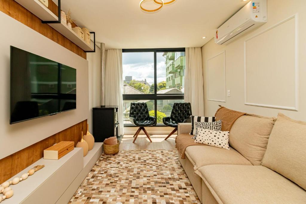 ein Wohnzimmer mit Couch und großem Fenster in der Unterkunft Apto Moderno e Confortável no Coração de Canela in Canela