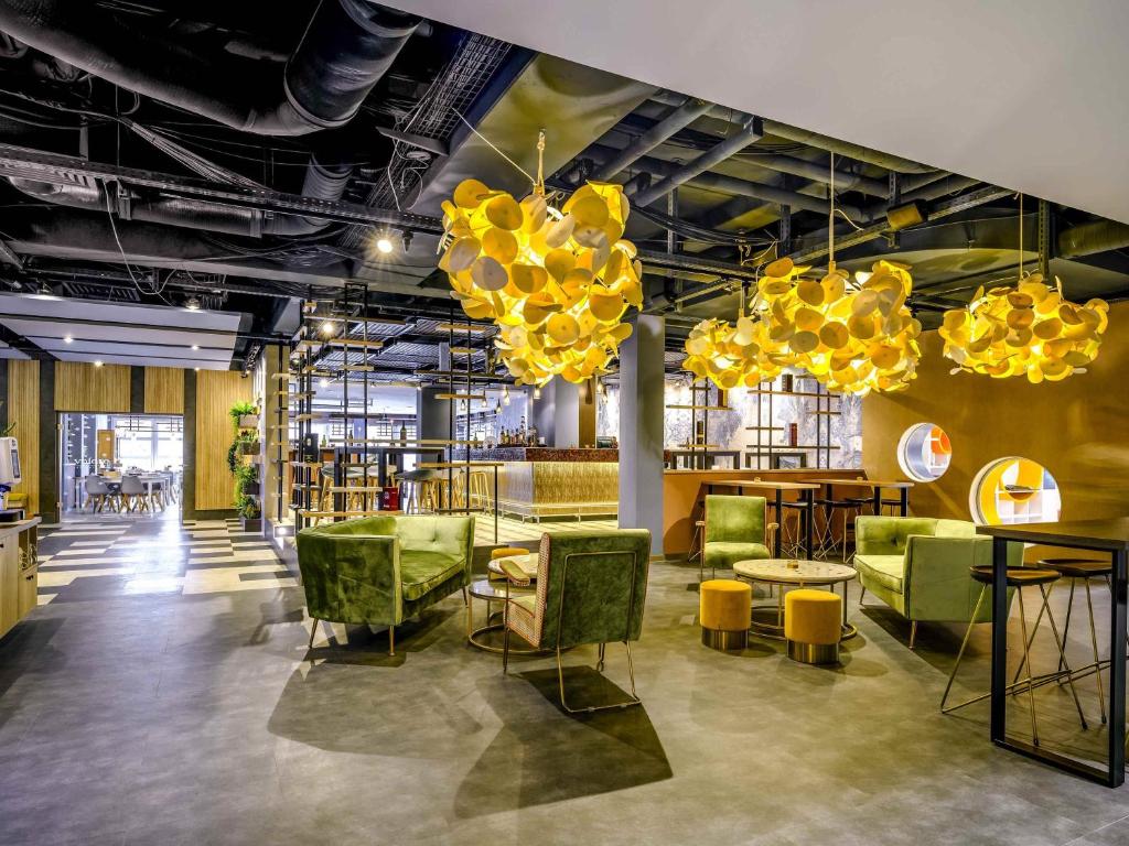 een kamer met groene stoelen, tafels en kroonluchters bij Ibis Styles Regensburg in Regensburg