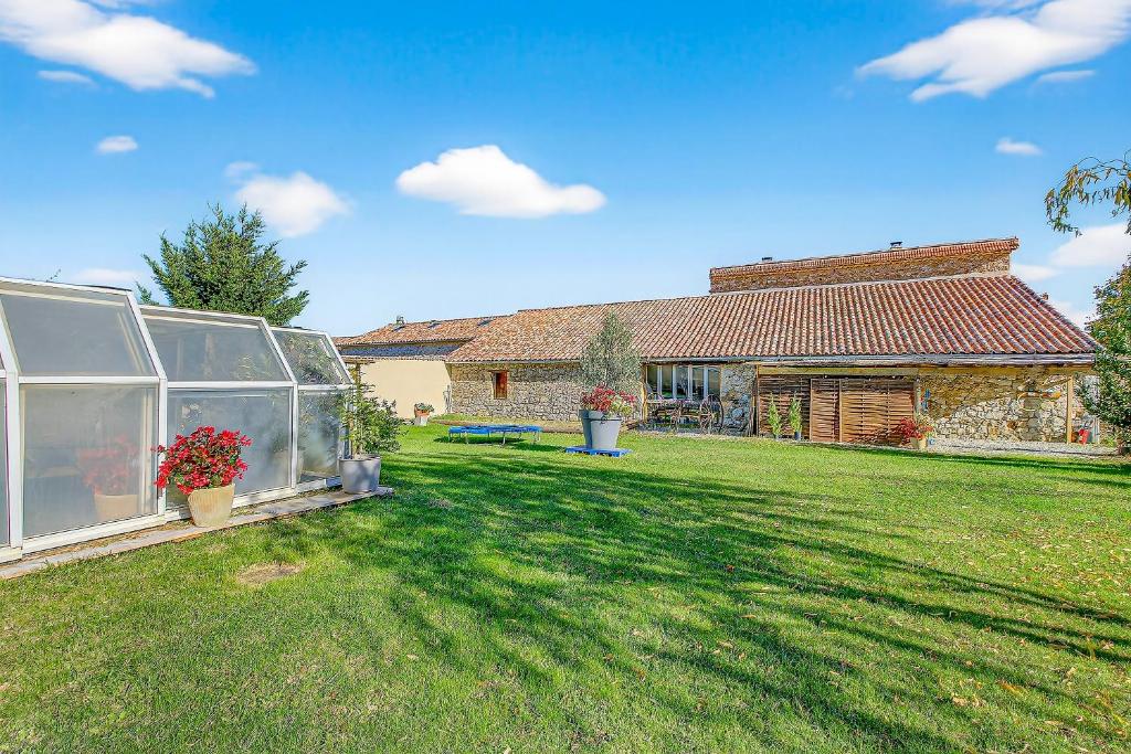 a greenhouse in the yard of a house at Gîte Uncinatum - La Grange Du Logis in Villevieille