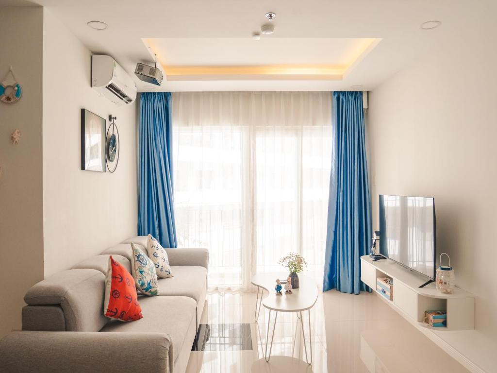 a living room with blue curtains and a couch at 2BR Luxury riverview - Melody of the Sea Monarchy in Da Nang