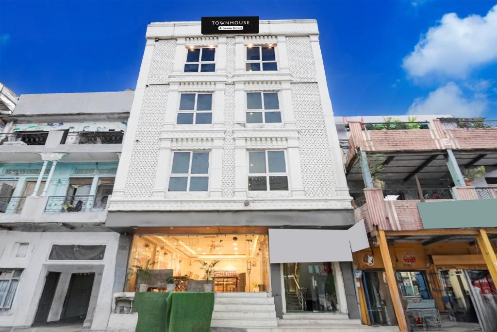 a tall white building with a sign on it at Super Townhouse Kali Ghat Prayagraj Formerly Ramesh Palace in Prayagraj
