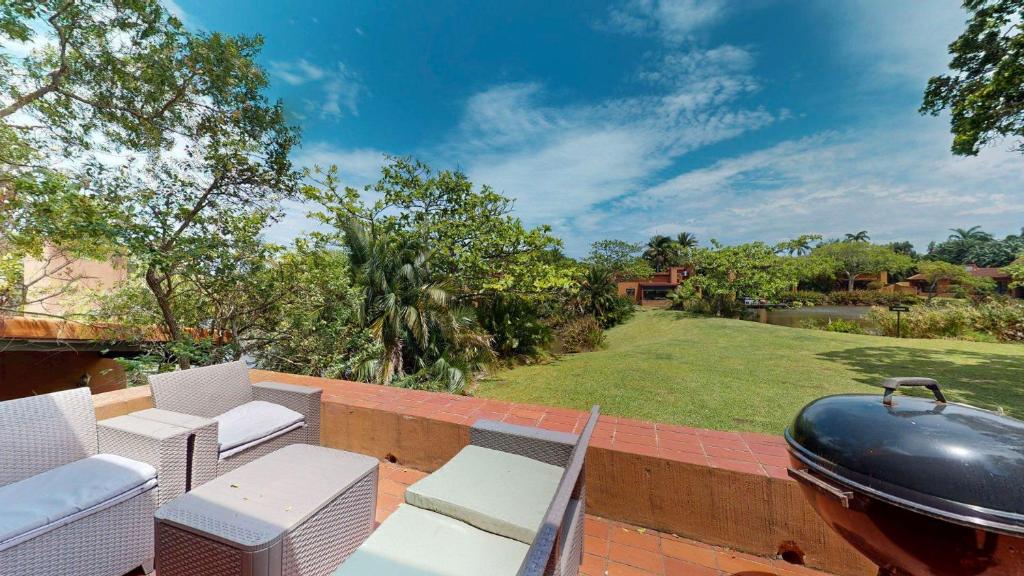 a patio with chairs and a grill and a yard at San Lameer Serenity by Top Destinations Rentals in Southbroom