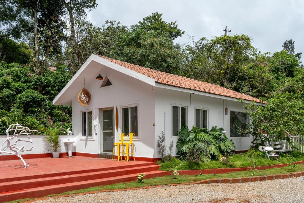 a small white house with yellow chairs in the yard at Lolo's by Raho - Loft Stay in Coorg in Ammatti