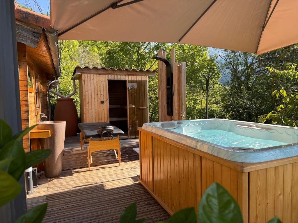 a hot tub on a wooden deck with an umbrella at Chalet d hiver in Millau