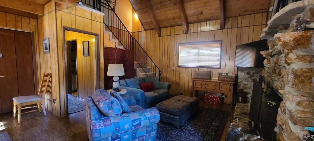 a living room with a blue couch and a chair at Lakeview Lodge, bookable boat slip! in Bass Lake