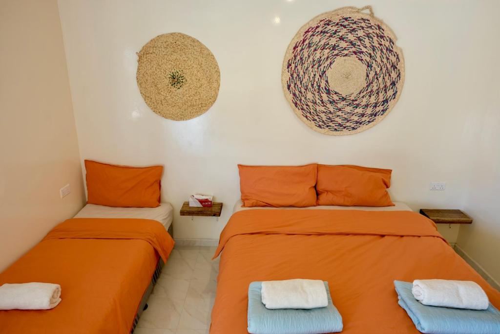 two beds in a room with orange sheets at Al Hudu Mountain House - Jebel Shams in Al Ḩayl