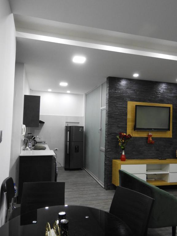 a living room with a kitchen and a tv on a wall at Suite de 4 camas cerca de UTPL y centro in Loja