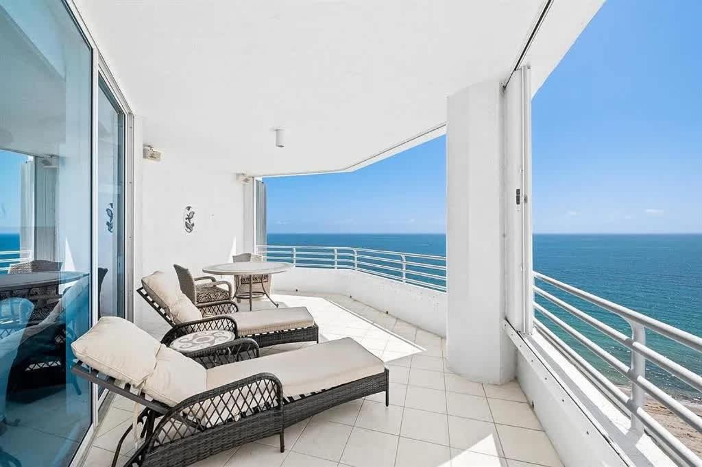 a balcony with chairs and a table and the ocean at Spacious Three-Bedroom Oceanfront Apartment with Panoramic Views in Pompano Beach