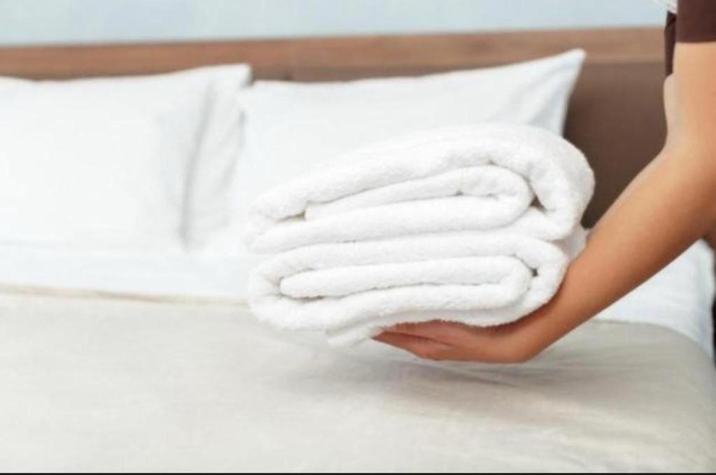 a woman is holding a stack of towels on a bed at UIM Mediterraneo PB Dolores Ibarruri Wifi in Puerto de Sagunto