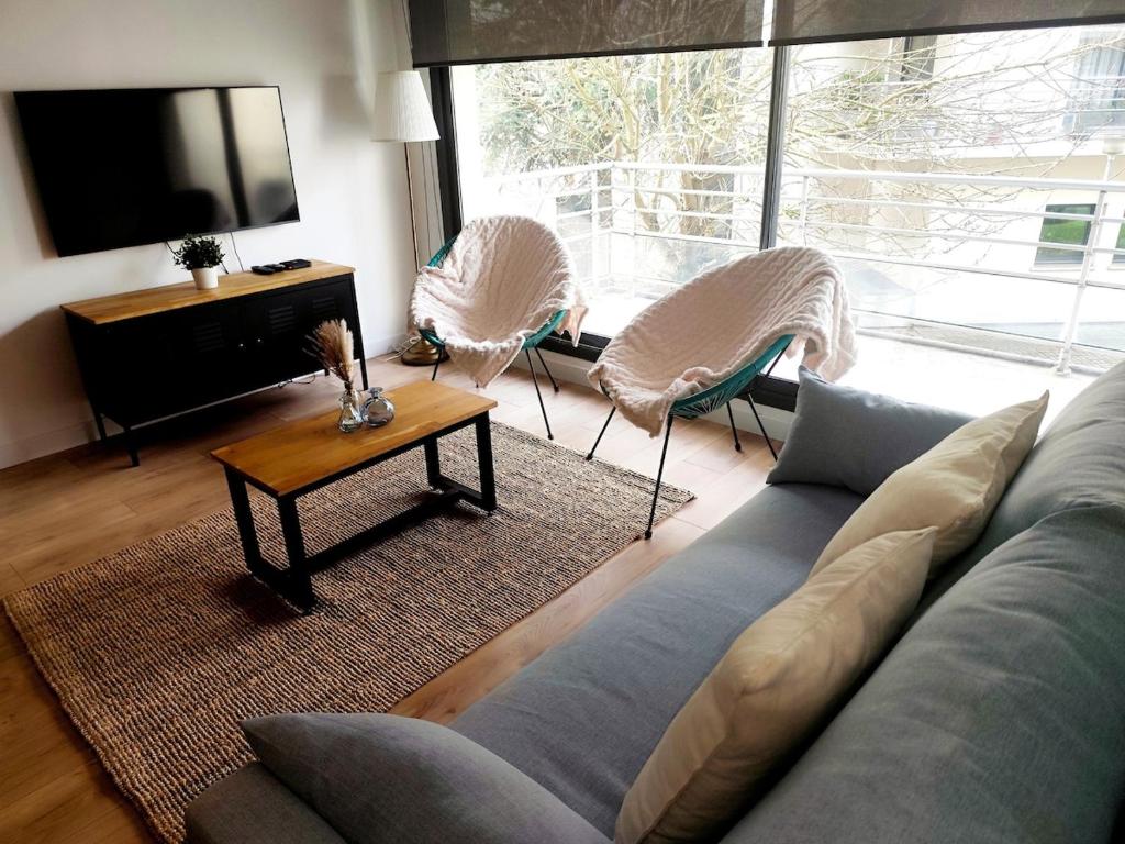 un salon avec un canapé et deux chaises dans l'établissement Appartement cosy en centre-ville, à Calais