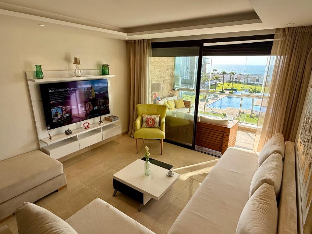 a living room with a couch and a tv at Sea View Apartment & Swimming Pool in Sidi Bouqnadel