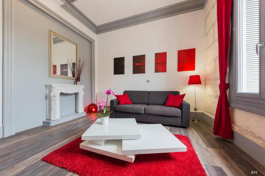 uma sala de estar com um sofá e um tapete vermelho em Du Guesclin Comédie (connecté & climatisé) em Montpellier
