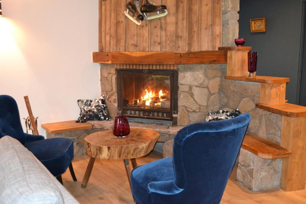 a living room with a fireplace and blue chairs at Chalet Mugnier in Samoëns