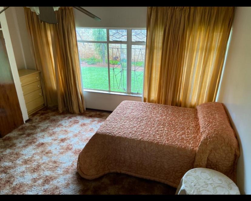 a bedroom with a bed and a large window at Highway Haven in Stilfontein