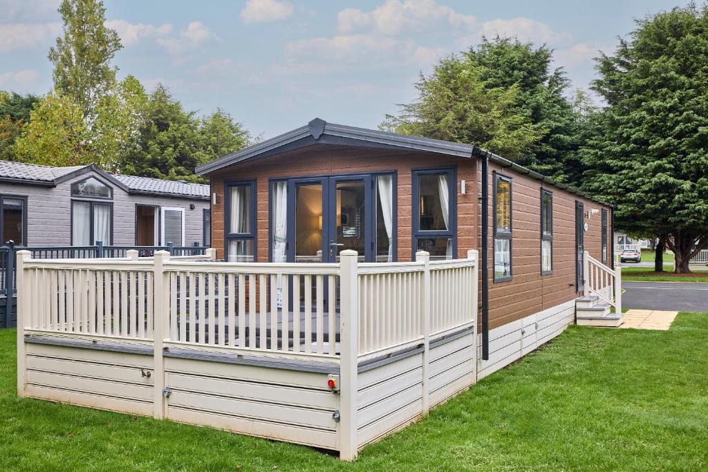 a tiny house with a white fence in a yard at Nightingale Lodge with Hot Tub in Barmby on the Moor