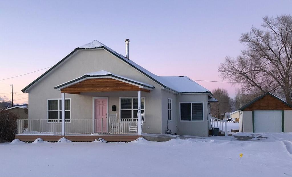 a white house with a porch in the snow at POEs Place in Panguitch
