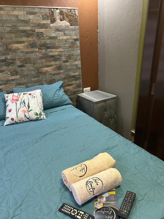 a bed with two towels and two remote controls on it at Lake boutique hotel empire in Thohoyandou