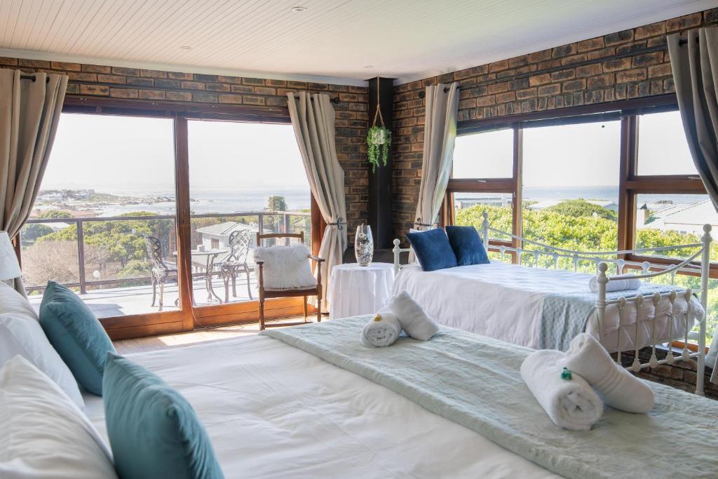 two beds in a room with large windows at White Shark Guest House in Gansbaai