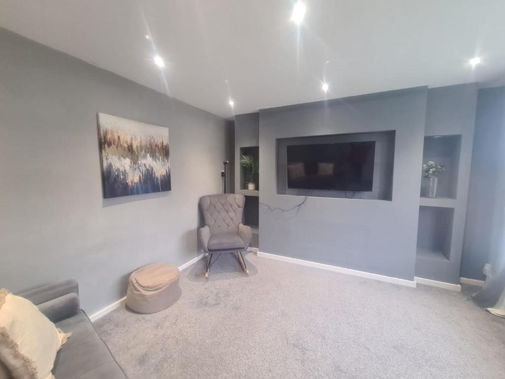 een woonkamer met een stoel en een flatscreen-tv bij Coastal town properties in Jarrow