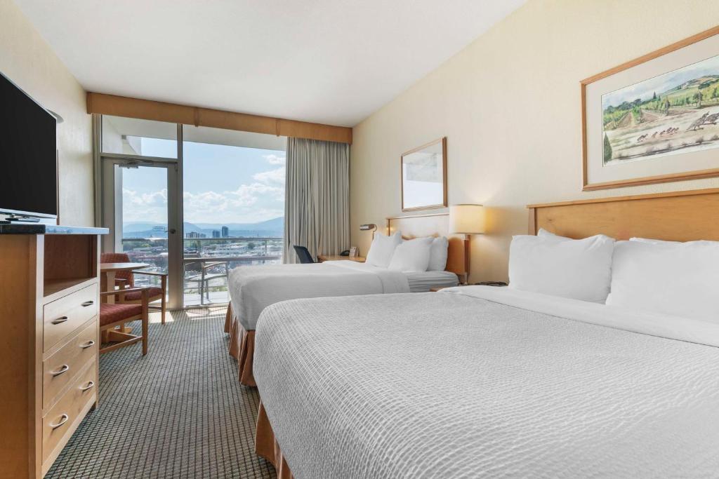 a hotel room with two beds and a television at Best Western Plus Kelowna Hotel & Suites in Kelowna